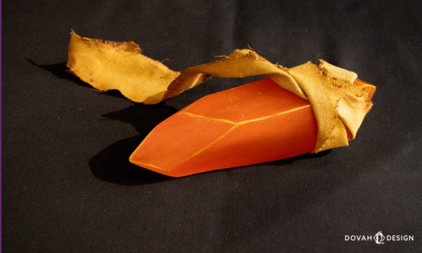 Closeup of a single Orange Guidance Soapstone, sitting on a black background.
