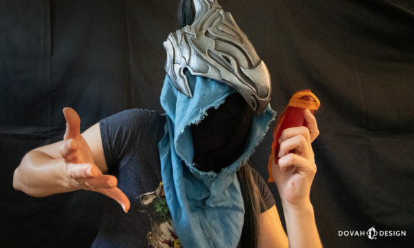 Sam of Dovah Design holding a red sign soapstone, talking in to it like a telephone while wearing Knight Artorias' helmet.