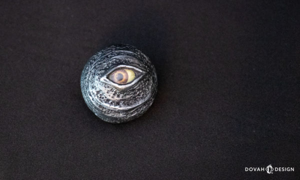 Single Black Eye Orb prop, sitting on a black background, taken from above with the eye looking off to the left.