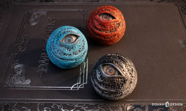 Red, Blue, and Black Dark Souls "Eye Orb" props, staggered and facing the camera, sitting on a "Dark Souls" Design Works book.