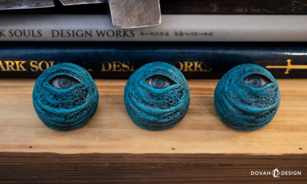 Set of three "Blue Eye Orb" replica props, sitting on a box with a stack of "Dark Souls Design Works" books visible behind them.