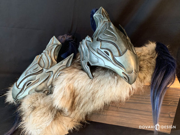 Two finished cast Helms of Artorias, one facing left, one facing right. Placed carefully on a wooden box with white fur lining.