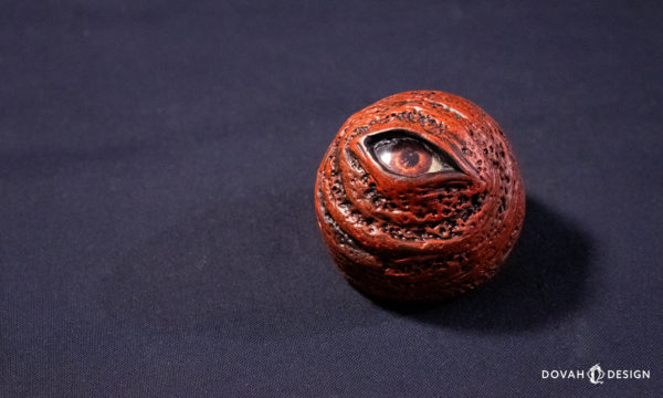 Single Dark Souls red eye orb replica prop, sitting on a black background with dramatic lighting.