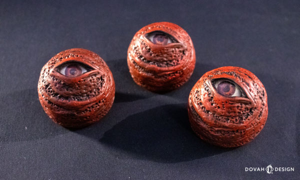 Group of three red eye orb prop replicas, sitting on black background.