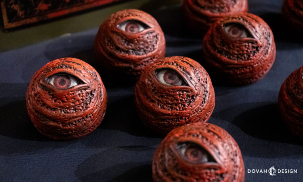 Close up group of six red eye orb props, facing various directions on a black background.