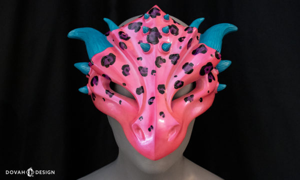 Hot pink and blue leopard spot dragon mask, facing foreward on black background.